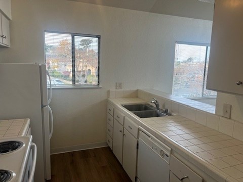 A kitchen with white appliances and wooden floors.
