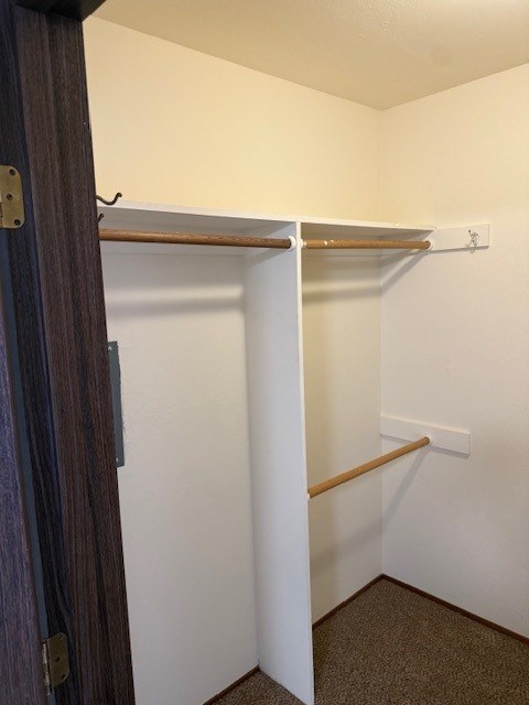 A white closet with a brown door and shelves.