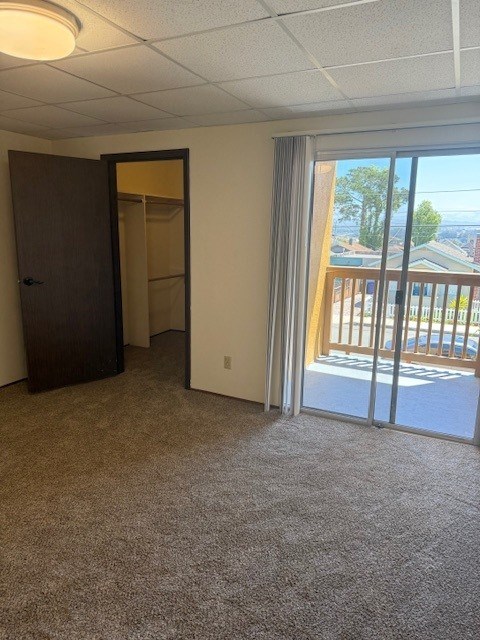 A room with a carpeted floor, a sliding glass door, and a wooden door.