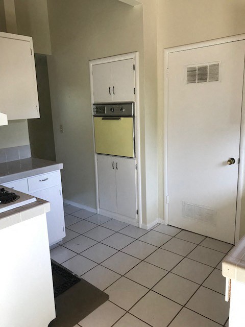 A kitchen with white cabinets and a white door.