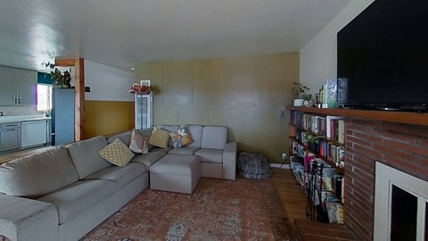 A living room with a grey couch and a fireplace.