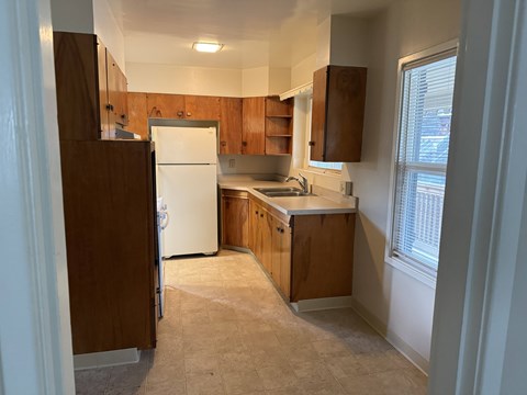 A kitchen with a white refrigerator and wooden cabinets.