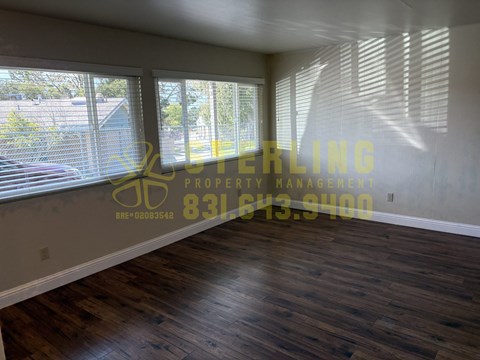 A room with wooden flooring and a window with blinds.