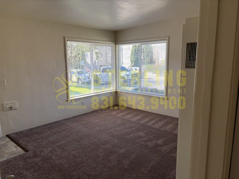 A room with a carpeted floor and a large window overlooking a parking lot.