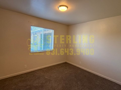 A room with a carpeted floor and a window covered with blinds.