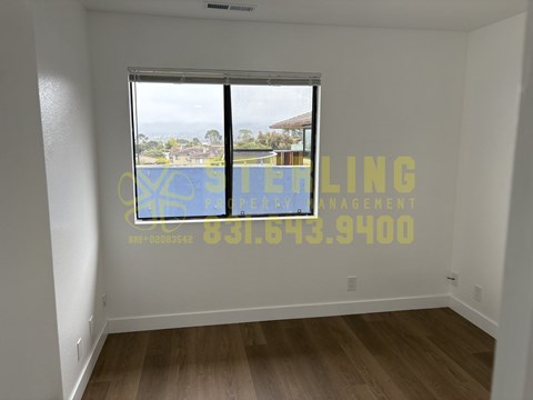 A room with a window and a phone number written on the wall.