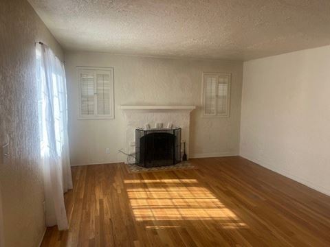 an empty living room with a fireplace and wooden floors