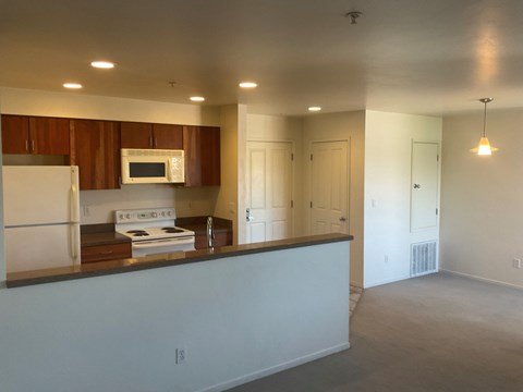 an empty kitchen with white appliances and wooden cabinets