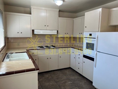 A kitchen with white cabinets and a white refrigerator.