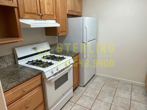 A kitchen with a stove, refrigerator, and cabinets.