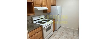 A kitchen with a stove, refrigerator, and cabinets.