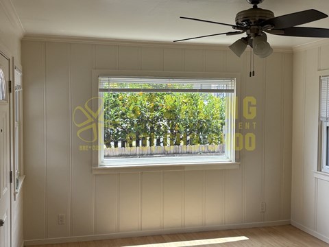 A room with a ceiling fan and a window showing a view of trees.