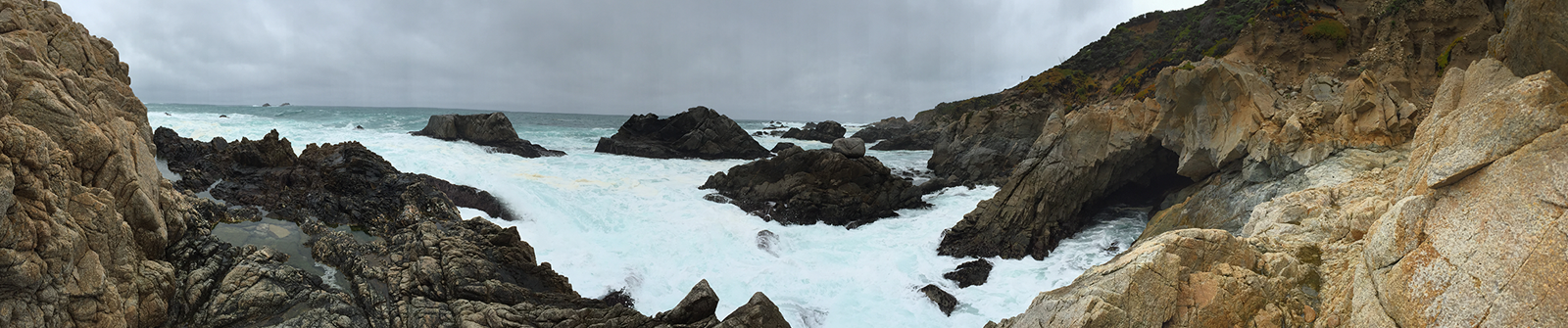 a view of the ocean with rocks and foam in the water