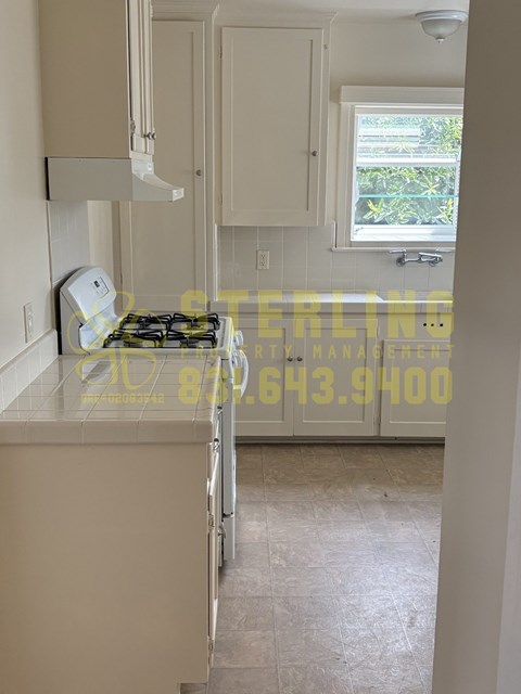 A kitchen with a stove top oven and cabinets.