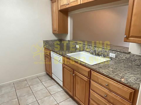 A kitchen with a granite countertop and wooden cabinets.