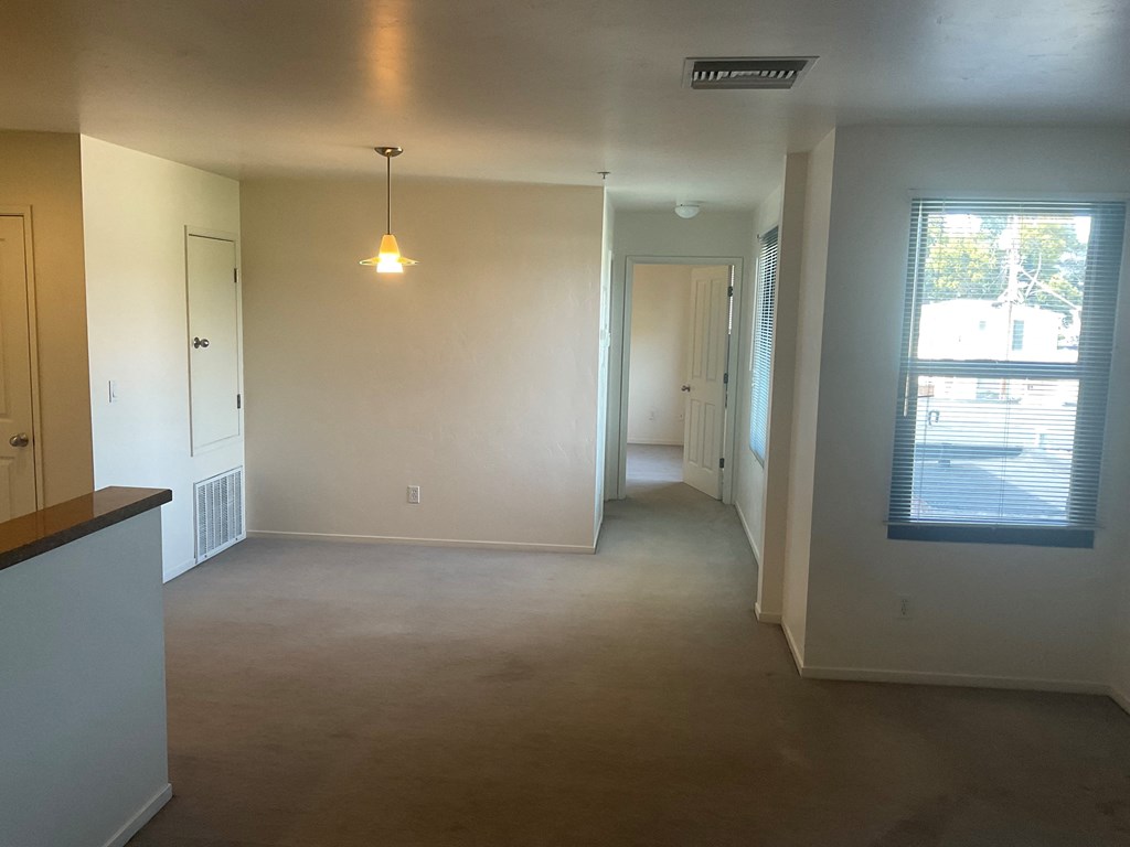 an empty living room with white walls and a window