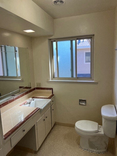 a bathroom with a toilet and a sink and a window