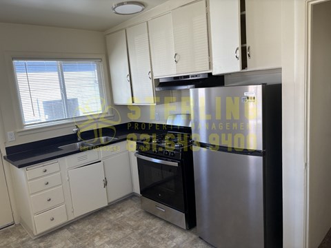 A kitchen with a refrigerator, oven, and cabinets.