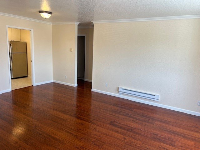 an empty living room with wood floors and a refrigerator