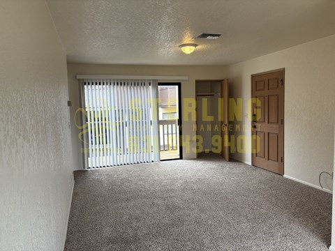 A room with a carpeted floor and a window with blinds.