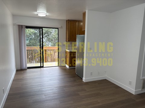 A room with a wooden floor and a sliding glass door leading to a balcony.