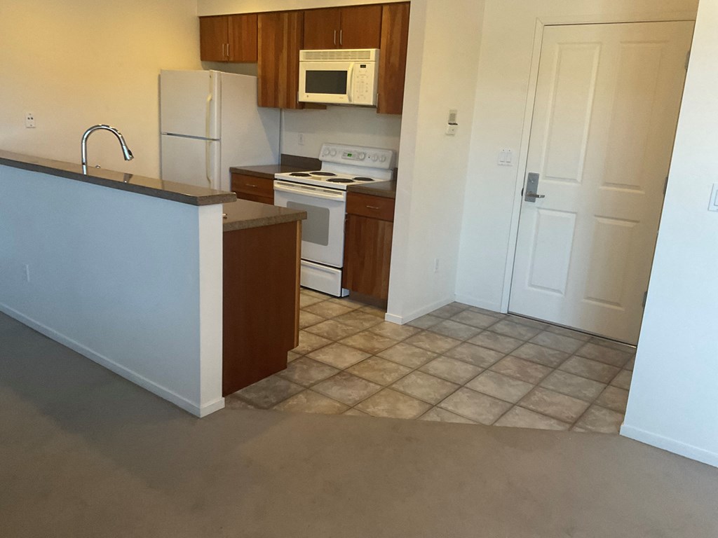 an empty kitchen with white appliances and a counter
