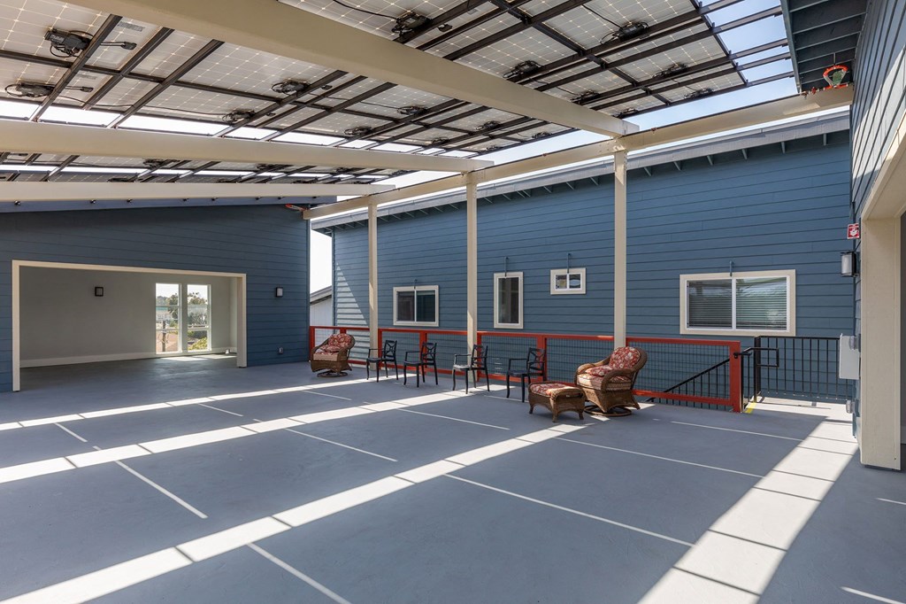 the courtyard of a blue building with chairs and a bench