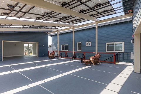 the courtyard of a blue building with chairs and a bench