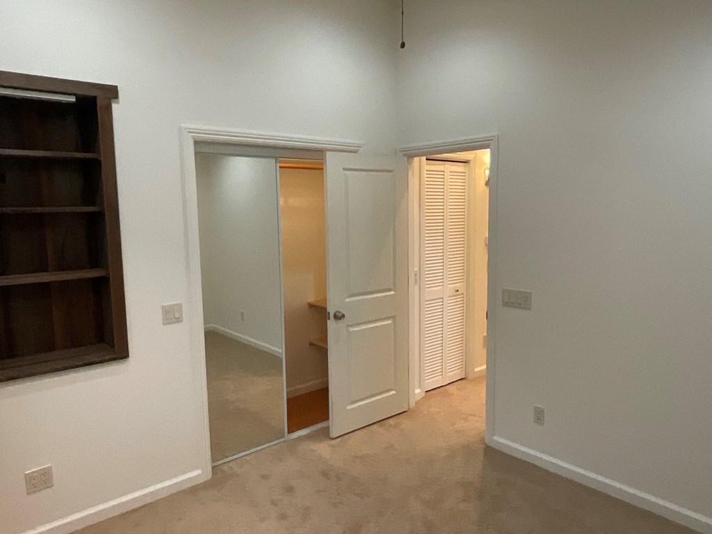 a living room with a door to a hallway and a closet