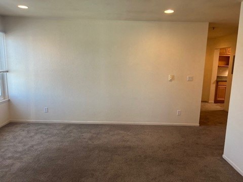 an empty living room with white walls and carpet