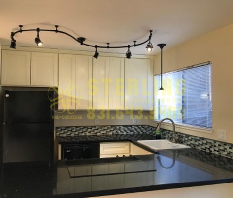 A kitchen with black and white tiles and a black fridge.