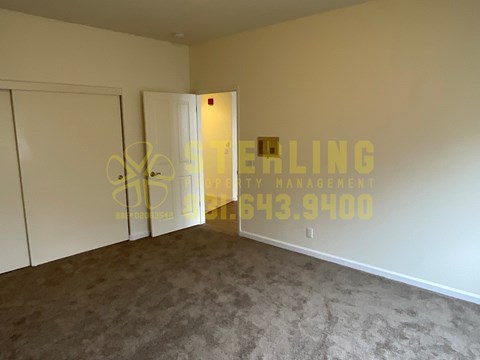 A room with a carpeted floor and a door on the right side.