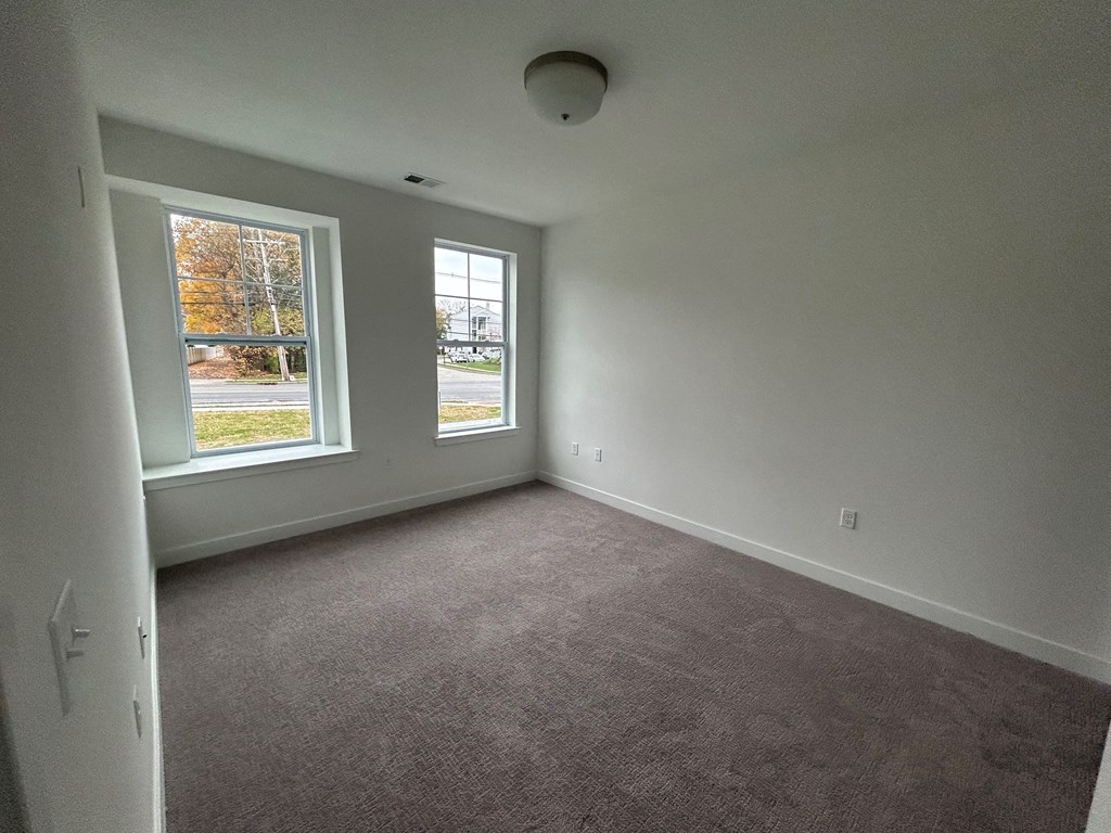 the living room of a house with carpet and a window