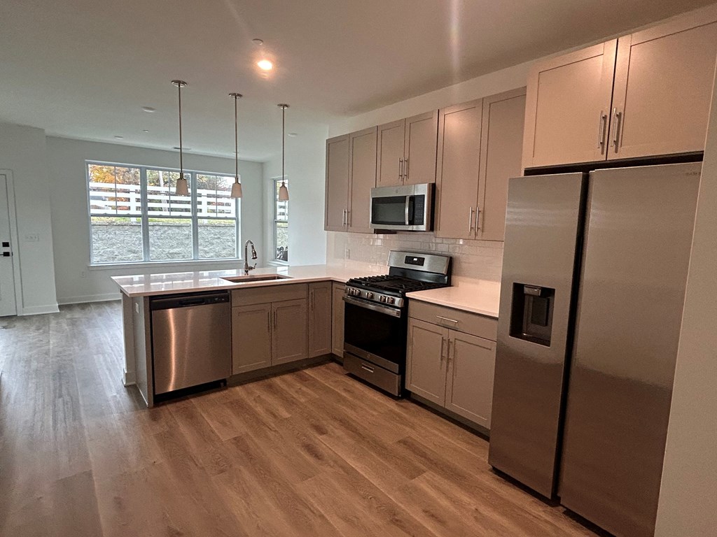 a kitchen with stainless steel appliances and wooden floors