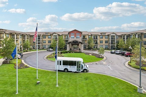 A white bus is parked in front of a building with a flag on a pole.