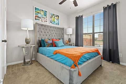 a bedroom with a bed with an orange blanket and blue pillows