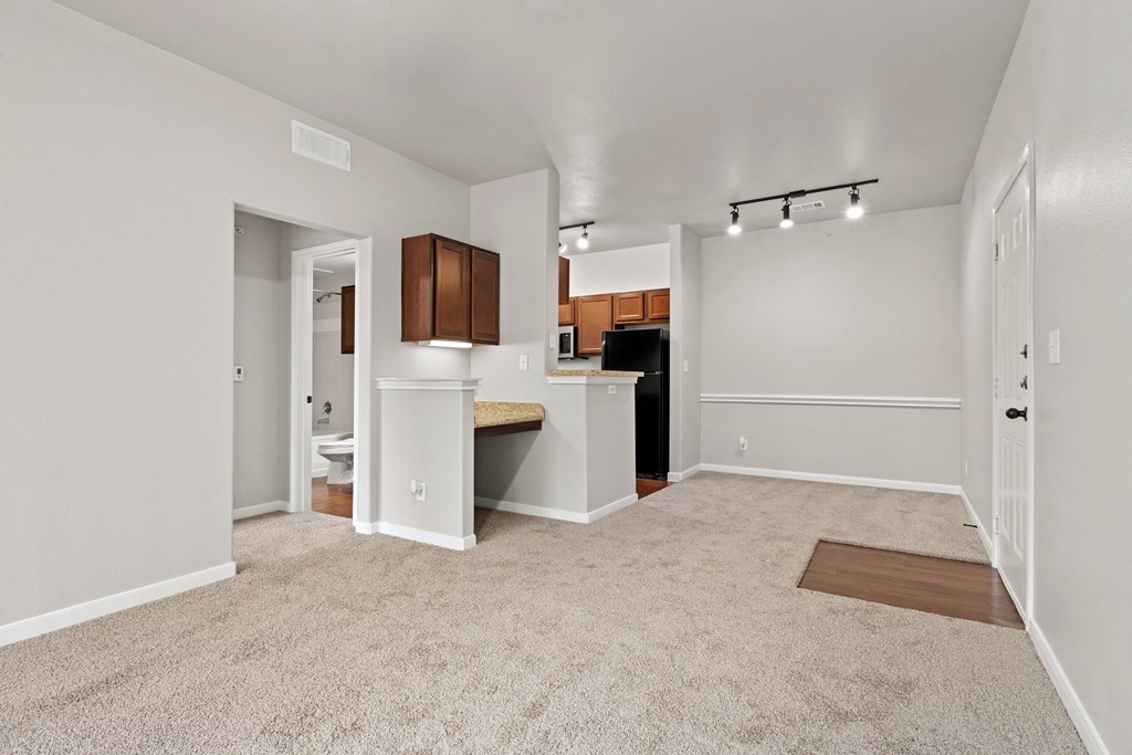 an empty living room with a kitchen with a sink and a window at Bella Madera Apartments, Lewisville, TX 75056