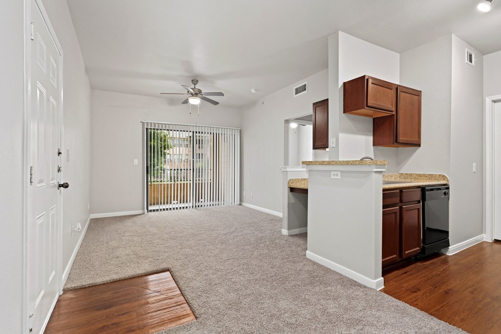 an empty living room with a kitchen and a ceiling fan at Bella Madera Apartments, Lewisville, TX 75056