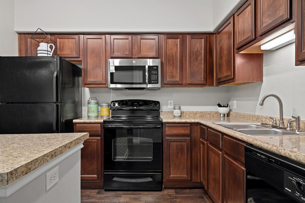 a kitchen with black appliances and granite counter tops at Bella Madera Apartments, Lewisville, TX