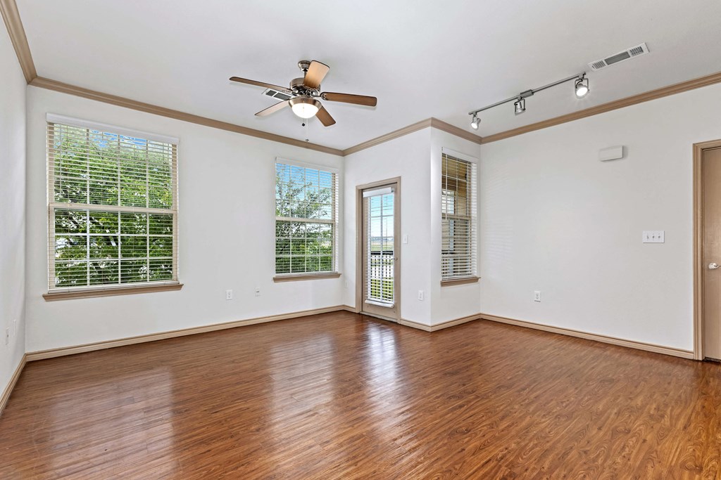 an empty living room with wood floors and a ceiling fan