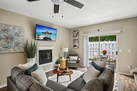 A living room with a grey couch, a fireplace, and a painting on the wall.