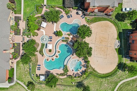 An aerial view of a park with a swimming pool and a sandy area.