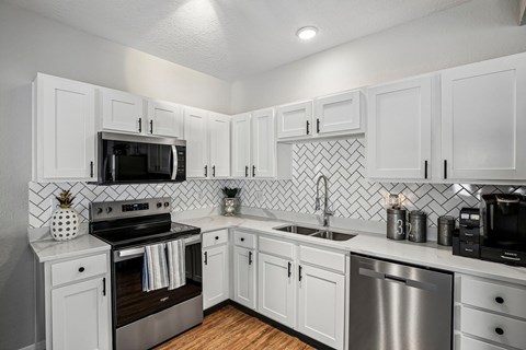 A modern kitchen with white cabinets and stainless steel appliances.