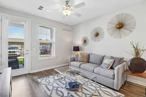 A living room with a grey couch and a glass coffee table.