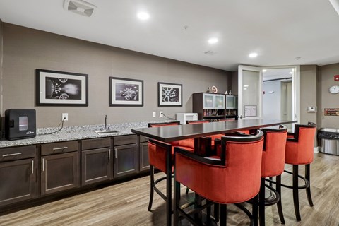 A kitchen with a table and chairs in the foreground and a fridge in the background.