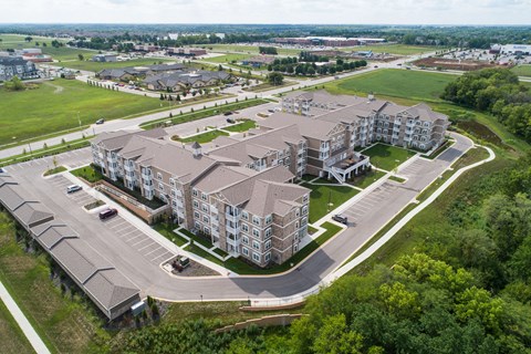 An aerial view of a large apartment complex surrounded by a parking lot and greenery.