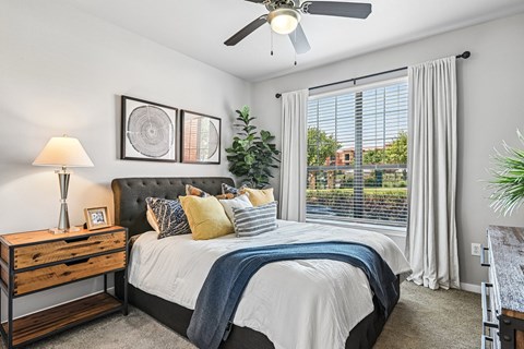 A bedroom with a bed, nightstand, and a ceiling fan.