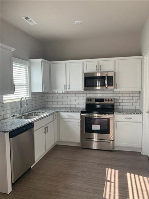 a kitchen with white cabinets and stainless steel appliances