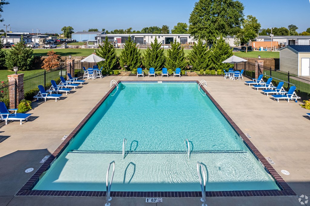 a swimming pool with blue chairs around it and a building in the background