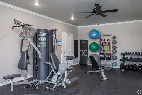 A home gym with a variety of equipment including a treadmill, weights, and a ceiling fan.